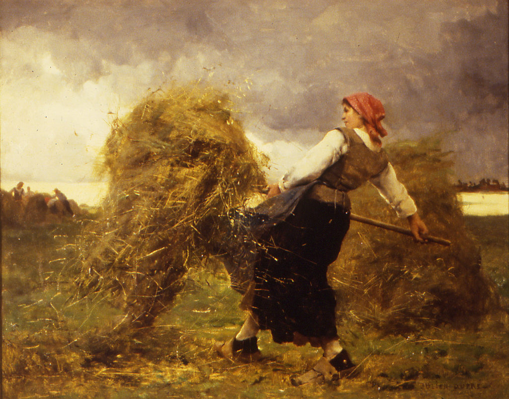 woman in a field carrying wheat