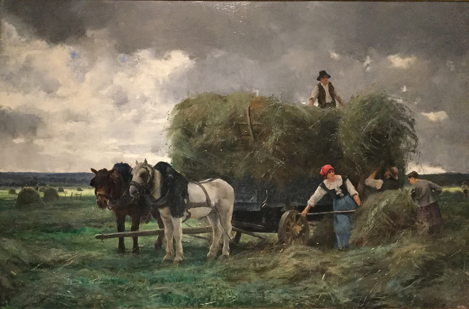 harvester in a field with a cart and horses