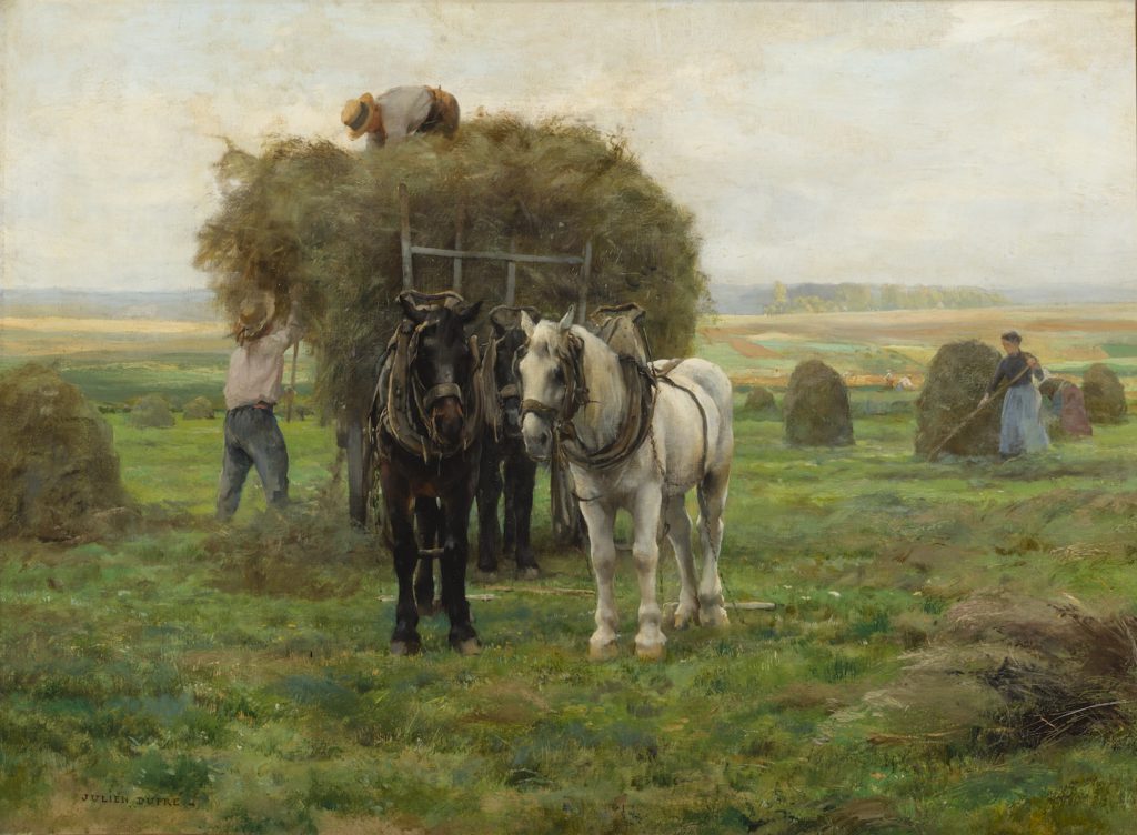two men loading a hay cart with a team one black horse and one white horse in the foreground.